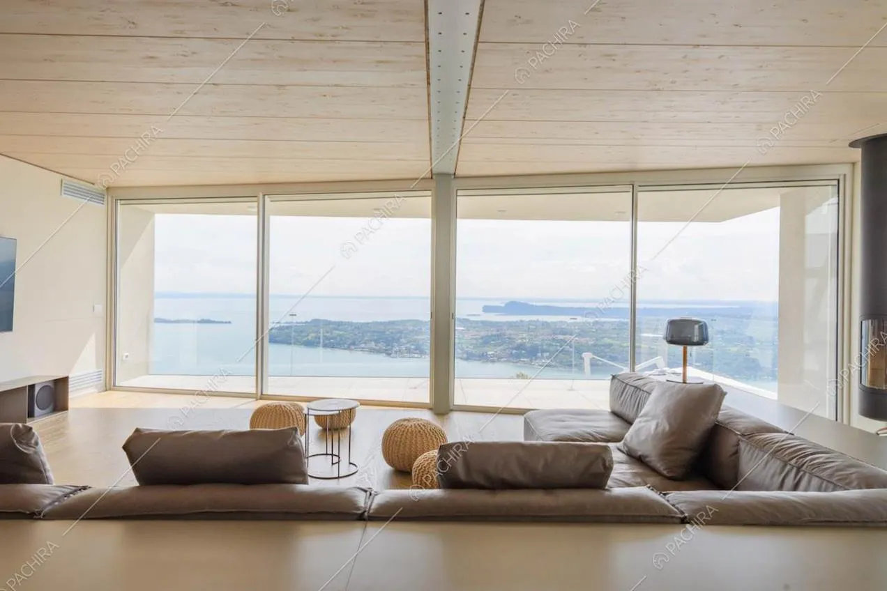 Divano marrone in pelle nel salotto con soffitto in legno e grandi vetrate