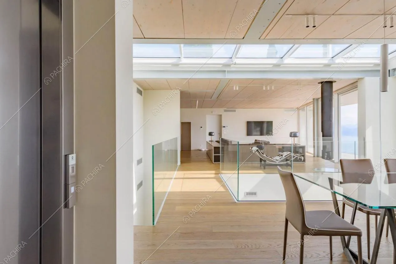 Ascensore nella grande sala con tavolo da pranzo, lucernari e pavimento in parquet
