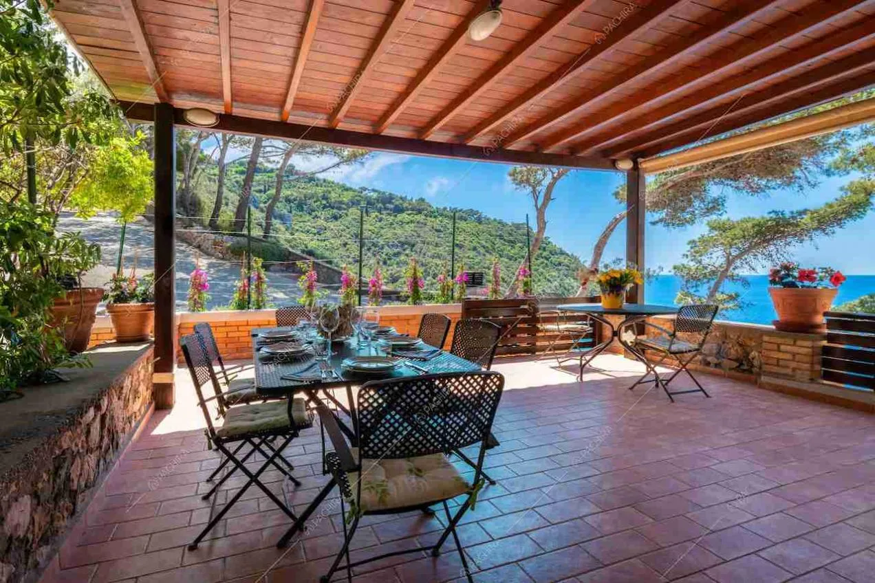 Veranda con soffitto in travi in legno, tavolo da pranzo e vista sul mare