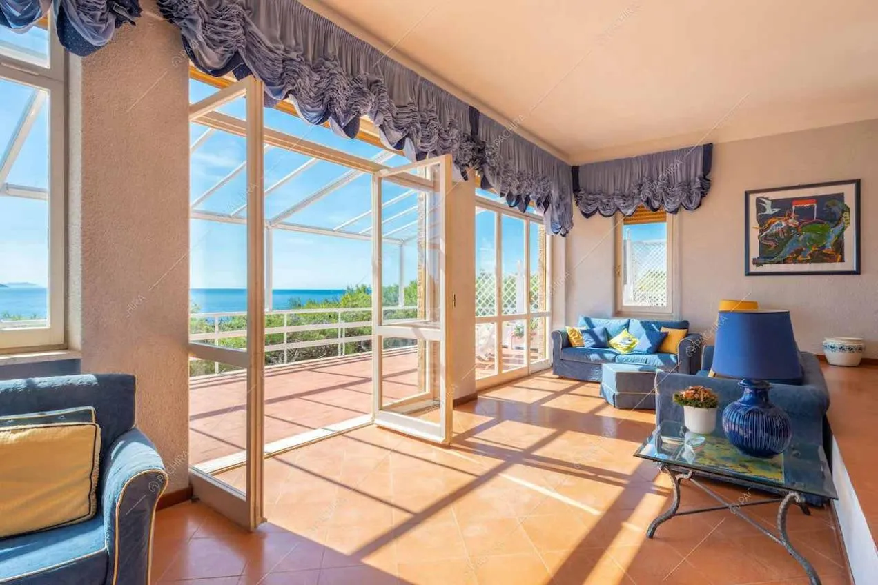 Salotto con divani e tende blu e porta-finestra per accedere alla terrazza