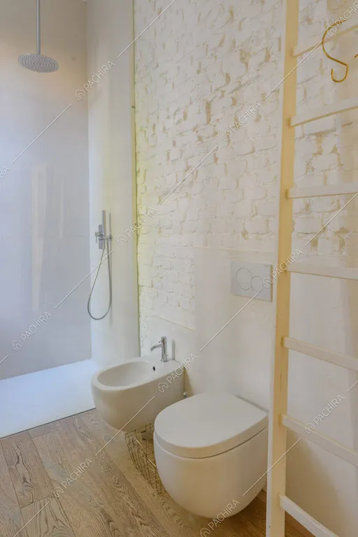 Parete in mattoncini a vista bianchi nel bagno con box doccia e pavimento in parquet