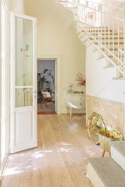 Luminoso atrio con pavimento in parquet, scale e pareti bianche