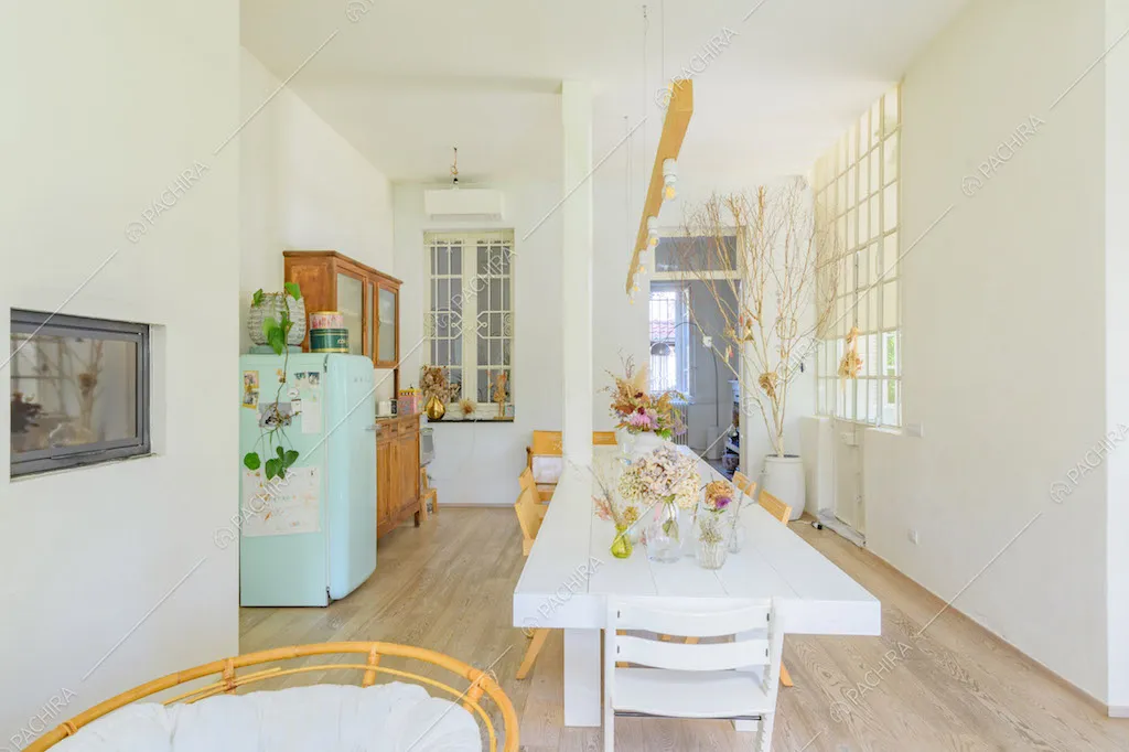 Dalla cucina vista sul tavolo da pranzo bianco nella zona living con pavimento in parquet