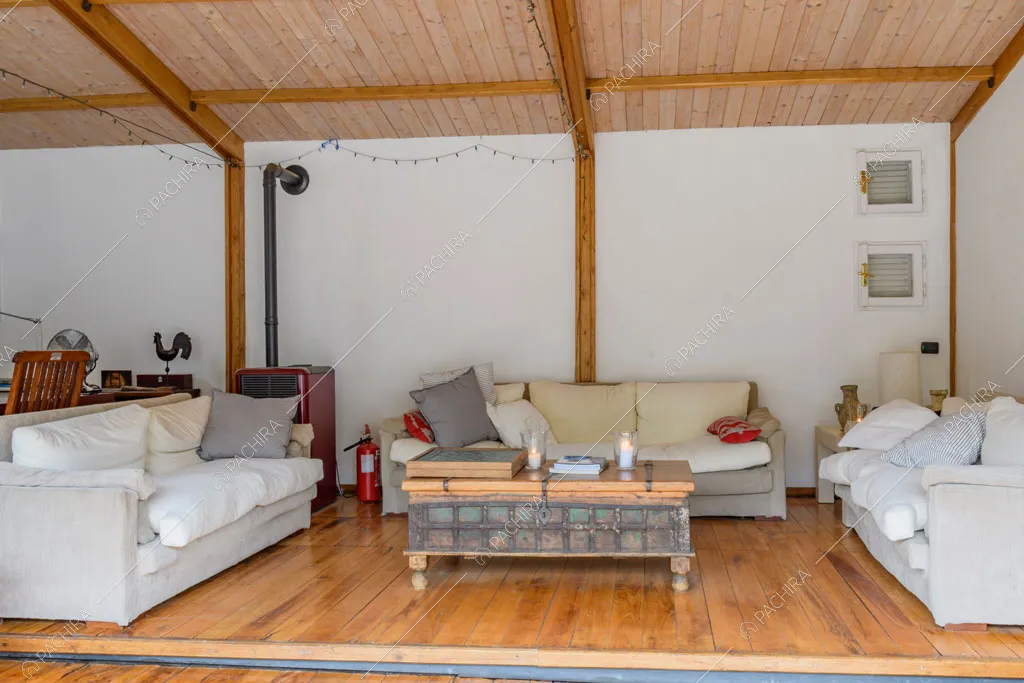 Sala con divani bianchi, pavimento in parquet, stufa e travi in legno sul soffitto