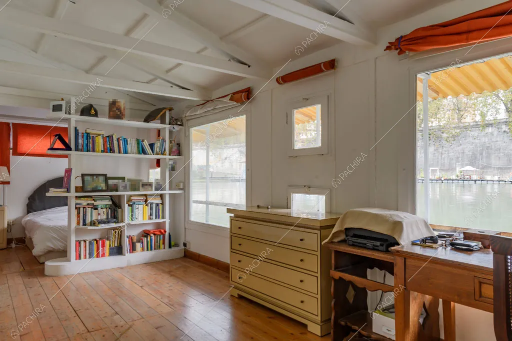 Travi a vista sul soffitto bianco, pavimento in parquet e letto matrimoniale
