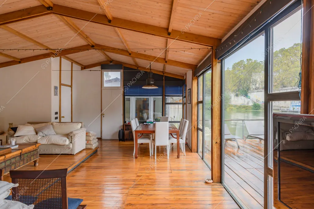 Grandi vetrate riempiono di luce naturale la sala con pavimento in parquet e soffitto in travi in legno