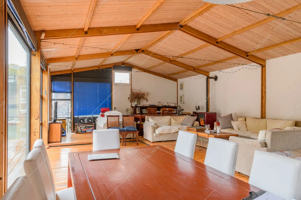 Tavolo da pranzo in legno nella grande sala con vetrate e divani bianchi