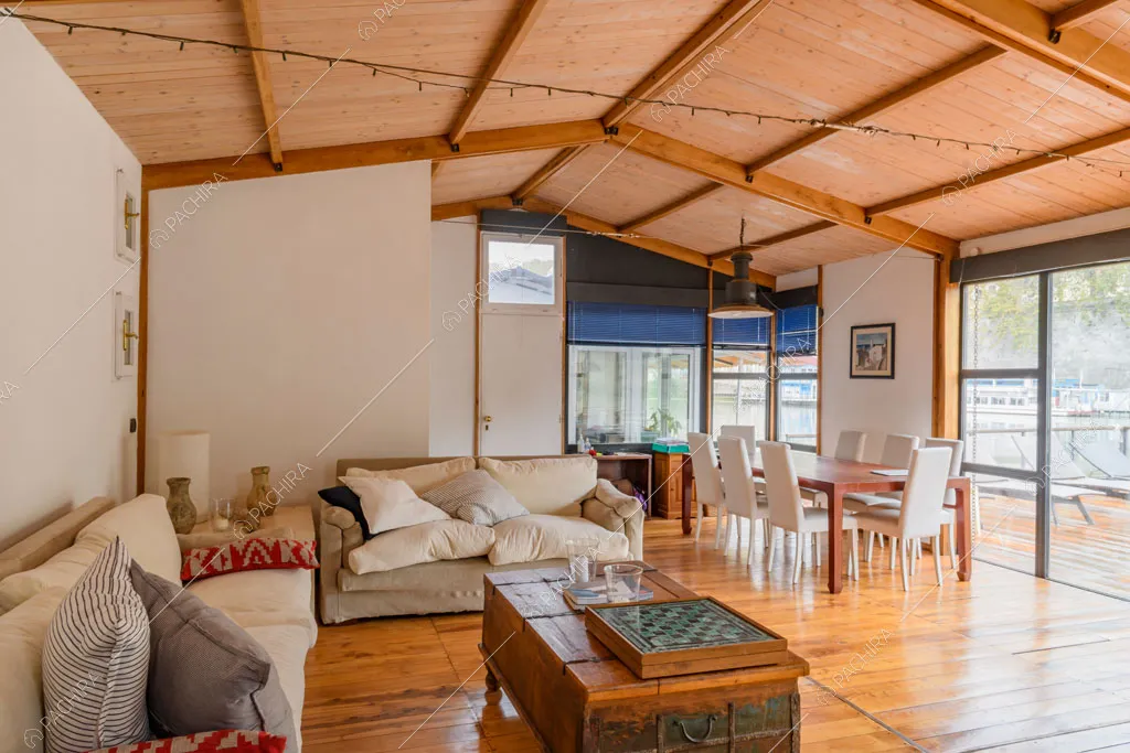 Travi in legno a vista sul soffitto, pavimento in parquet e grandi vetrate con vista sul Tevere