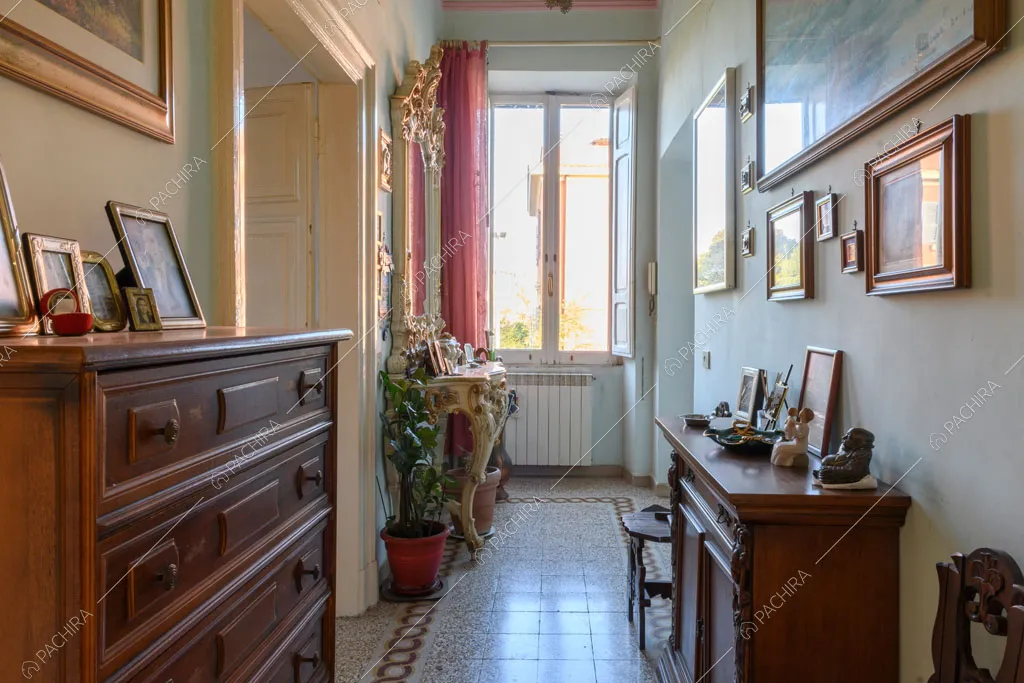 Luminoso corridoio con pareti bianche e pavimento in graniglia