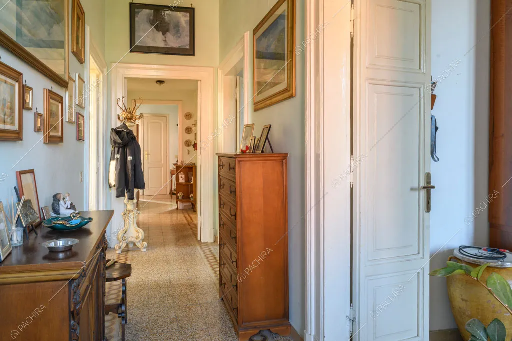 Corridoio con pavimento in graniglia e vista sulla porta bianca con boiserie