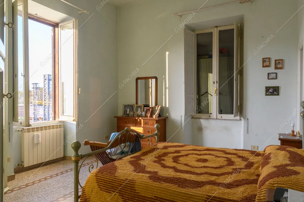 Ampia camera da letto matrimoniale con pareti azzurre e pavimento in graniglia