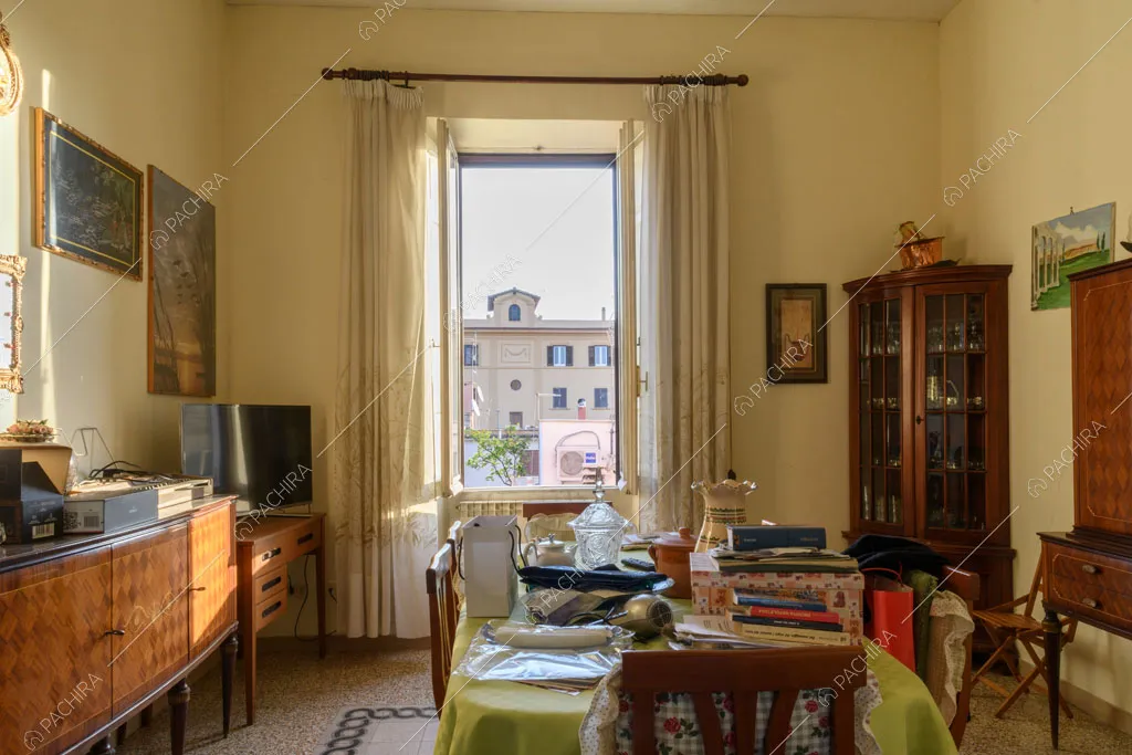 Luminosa sala da pranzo con pareti gialle, pavimento in graniglia e mobili antichi in legno