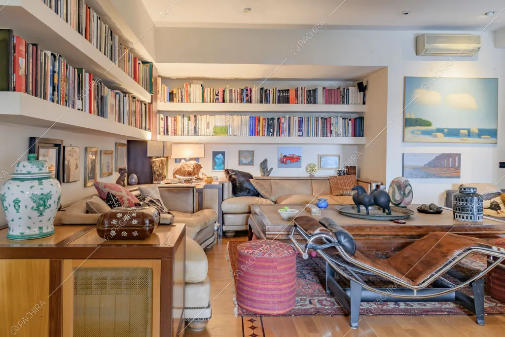 Libreria nella sala con divani di pelle, pavimento in parquet e poltrona di design