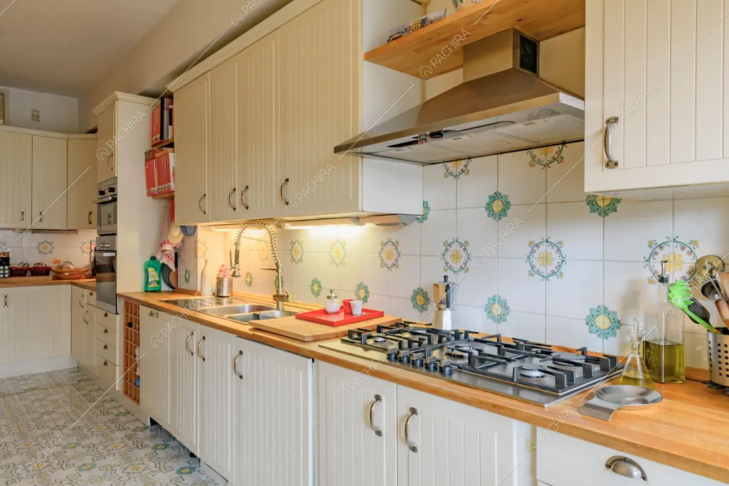 Fornelli a gas nella cucina a parete bianca con piano da lavoro in legno