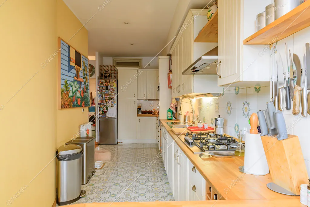 Cucina a parete bianca con fornelli a gas e pavimento in piastrelle