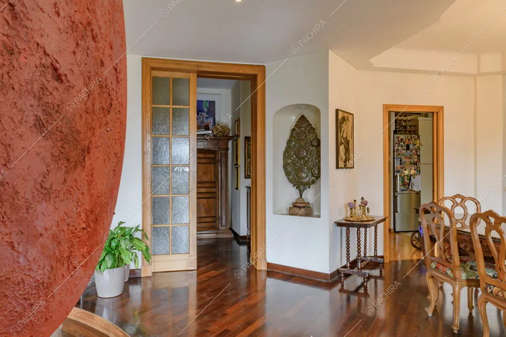 Pavimento in parquet e pareti bianche nella sala con scorcio sulla cucina