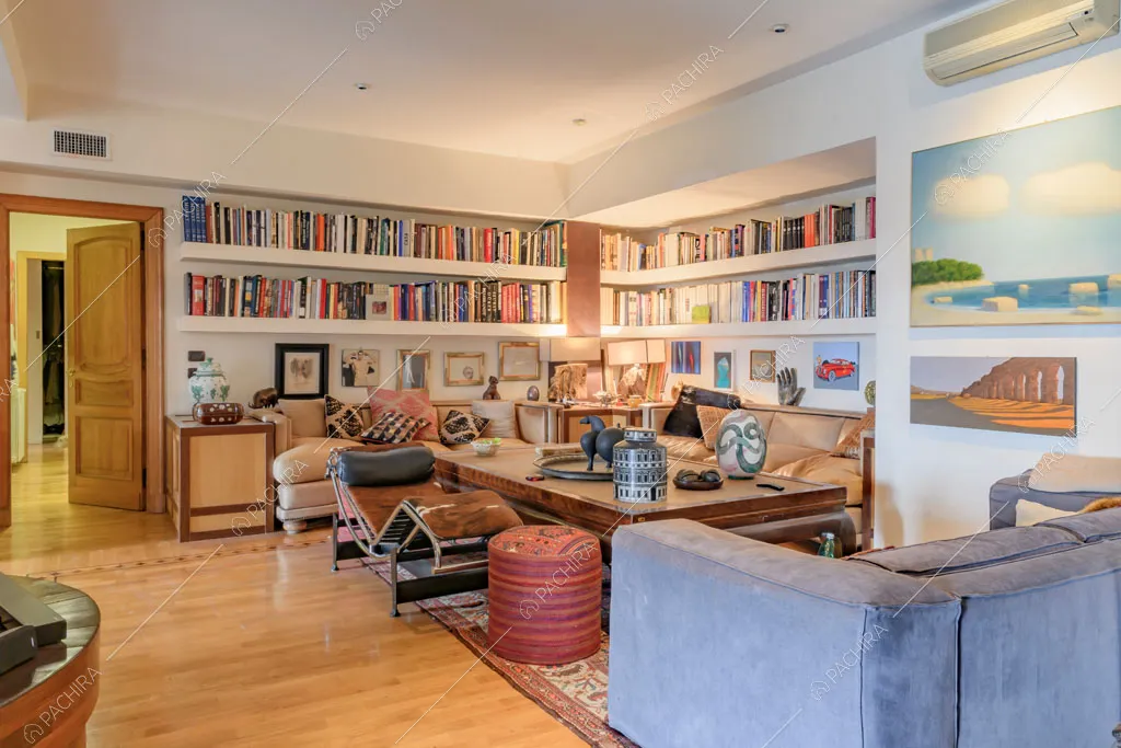 Pavimento in parquet nella sala con pareti bianche, divani e libreria