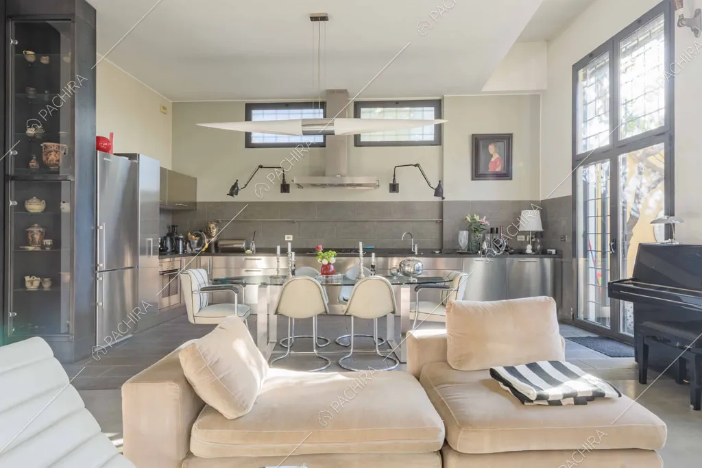 Pouf beige nella luminosa zona living con pavimento in cemento lisciato e cucina a parete
