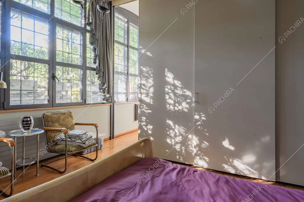 Ampie vetrate in stile industriale riempiono la camera da letto matrimoniale di luce naturale