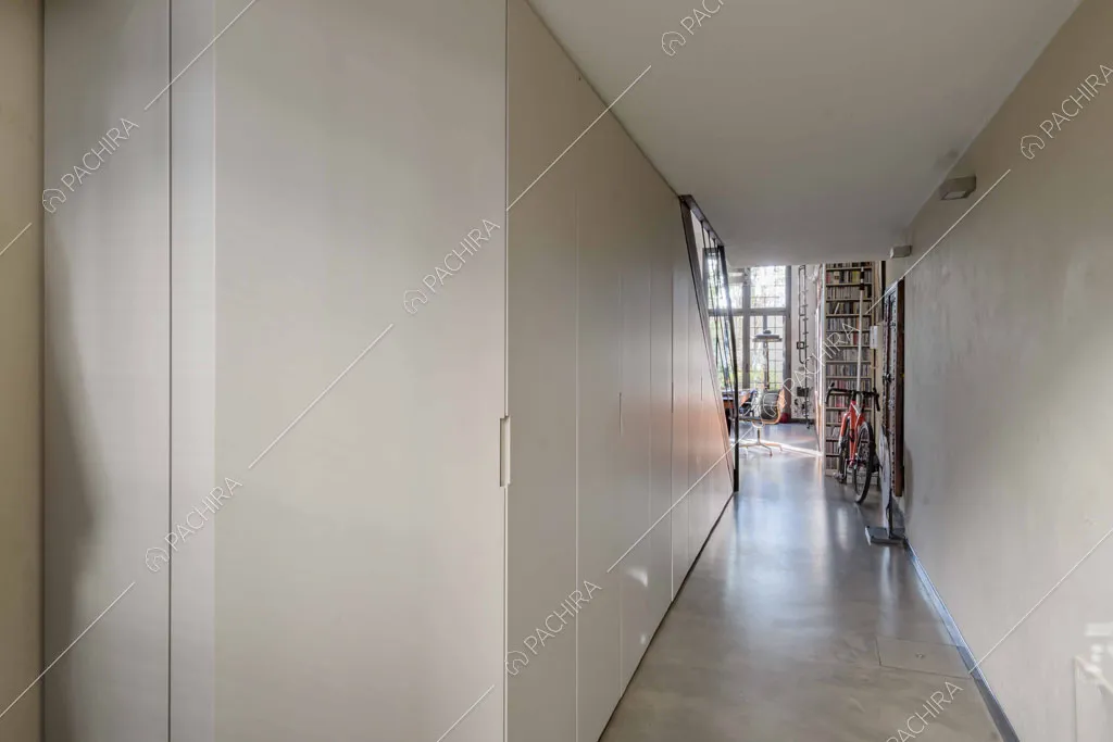 Lungo corridoio con scorcio sulla zona living, parete bianca e armadi a muro