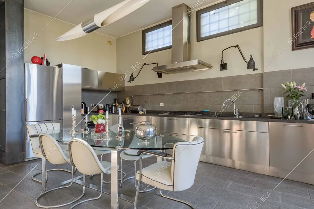 Tavolo da pranzo rotondo nella luminosa zona living con cucina a parete in acciaio