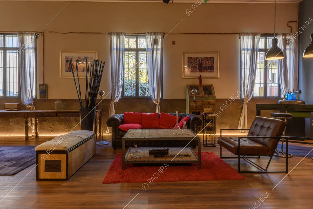 Poltrona marrone in pelle, pouf e divano nero nell'open space con pavimento in parquet