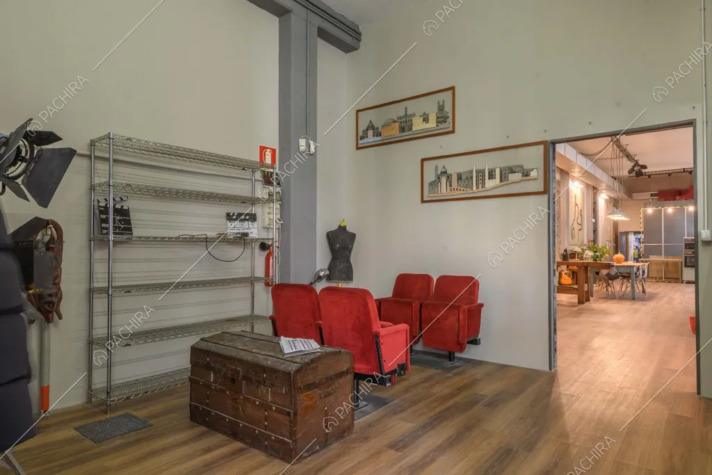 Poltrone rosse da cinema nell'atrio con pavimento in parquet e vista sull'open space