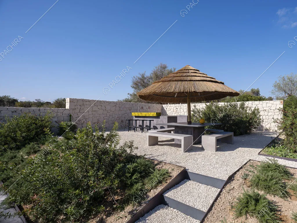 Giardino con ombrellone in paglia, panchine e mura bianche