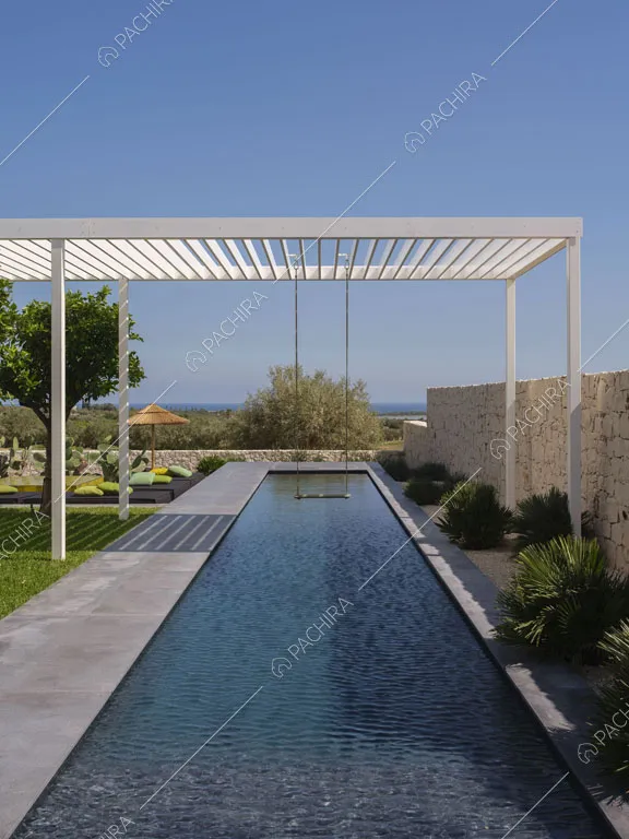Lunga piscina nel giardino circondato dalle mura di pietre bianche