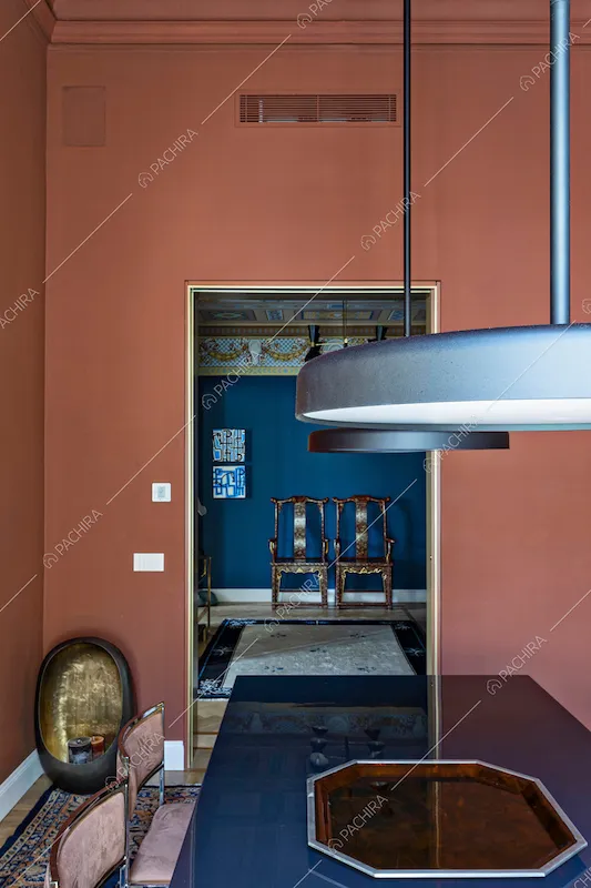 Lampadari di design nella sala da pranzo con tavolo blu e vista sull’atrio