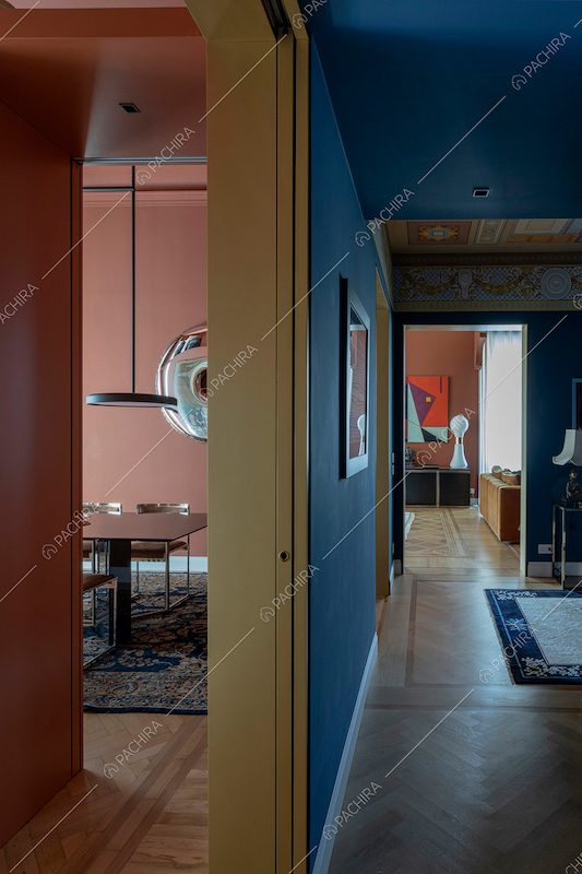 Vista sulla sala da pranzo e sul corridoio con pareti blu e pavimento in parquet