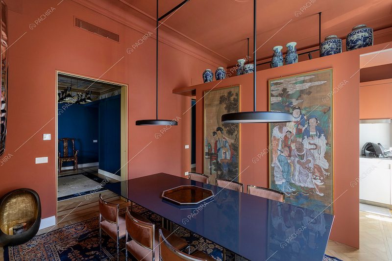 Tavolo da pranzo blu, lampadari di design e quadri in stile orientale nella sala