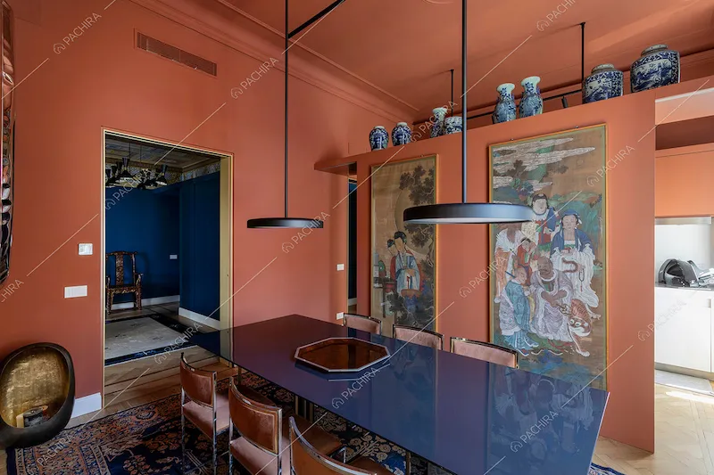 Tavolo da pranzo blu, lampadari di design e quadri in stile orientale nella sala