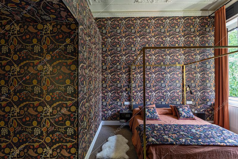 Carta da parati a tema floreale nella luminosa camera da letto con boiserie sul soffitto