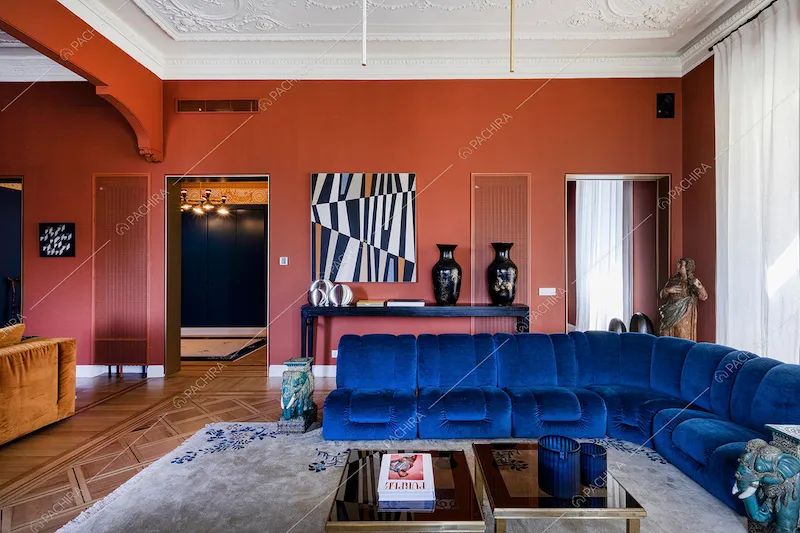 Divano in velluto blu nella luminosa zona living con boiserie sul soffitto