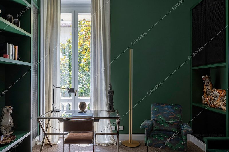 Studio con pareti verde scuro, scrivania e porta-finestra per accedere al balcone