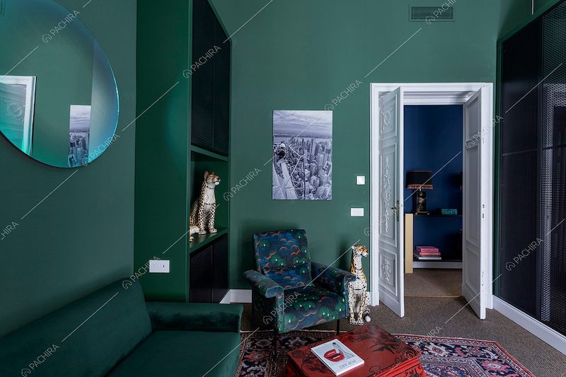 Pareti verdi dello studio con divanetto in velluto e moquette sul pavimento