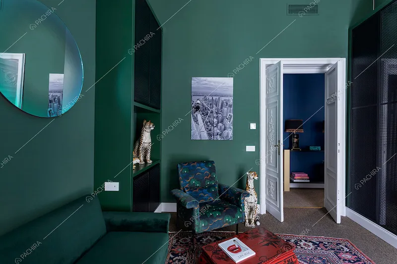 Pareti verdi dello studio con divanetto in velluto e moquette sul pavimento