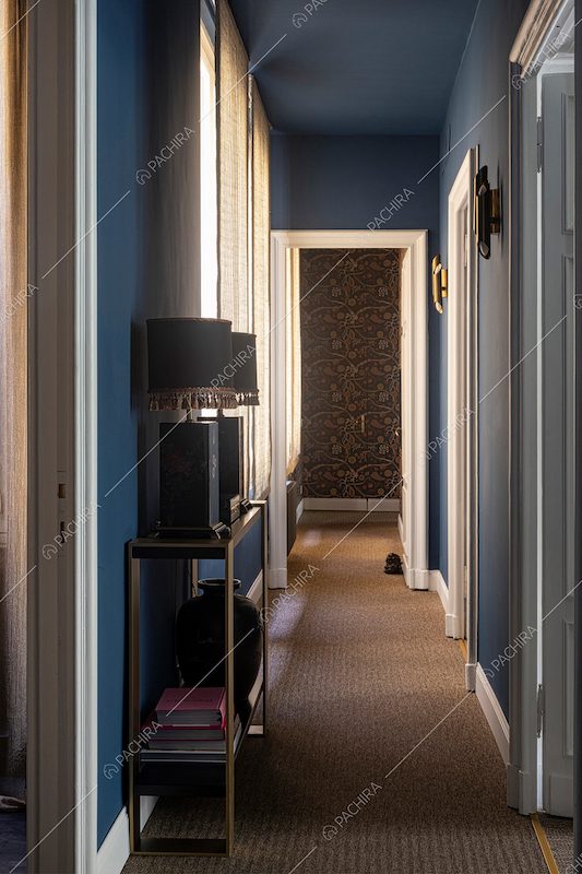 Lungo corridoio con pavimento in moquet e pareti e soffitto blu