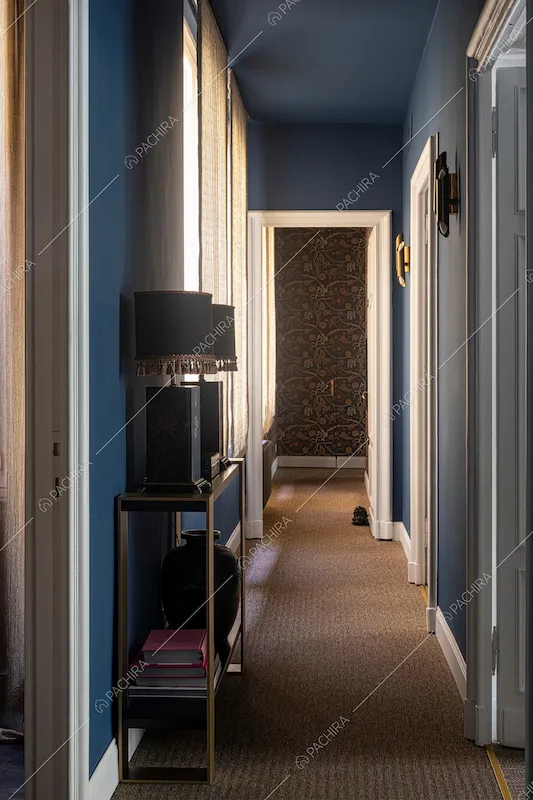 Lungo corridoio con pavimento in moquet e pareti e soffitto blu