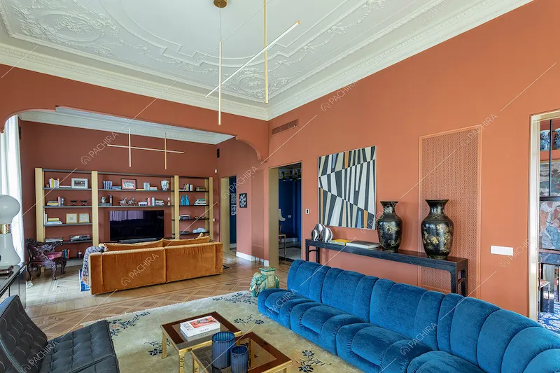 Ampia zona living con pareti color terra rossa, boiserie sul soffitto e pavimento in parquet