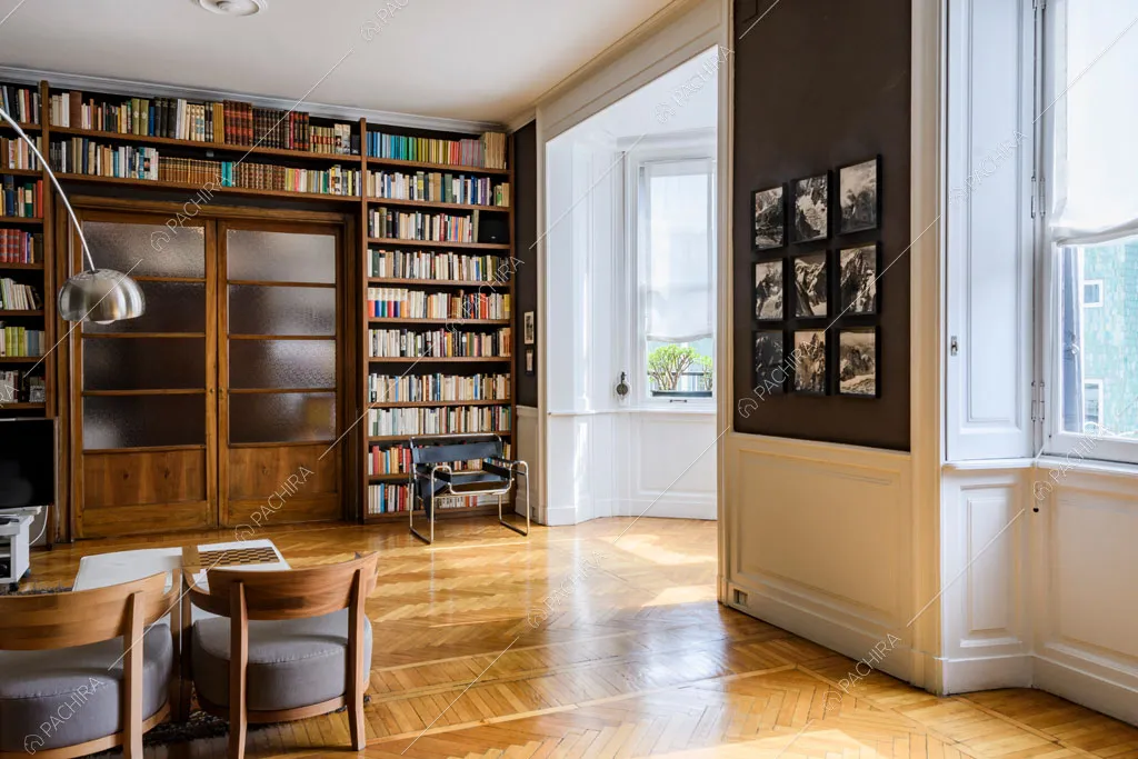 Bow window con boiserie nella luminosa sala con libreria a parete e porta a vetri antica