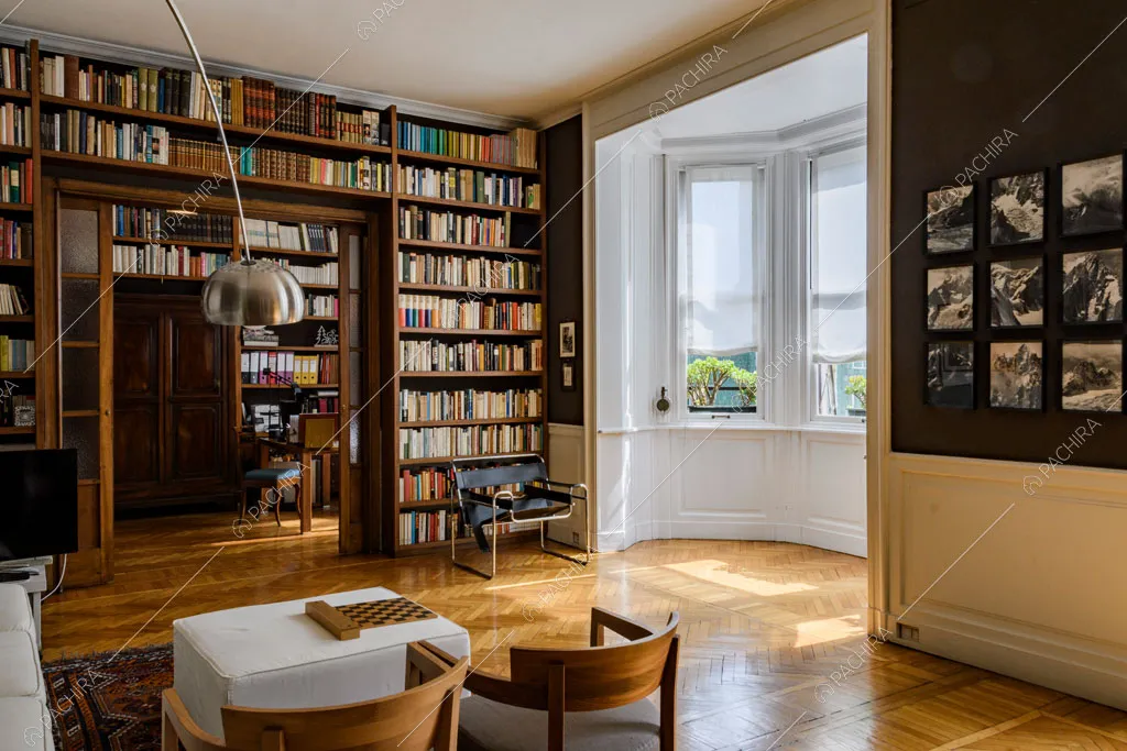 Pavimento in parquet a spina di pesce nella sala con libreria a parete e scorcio sullo studio
