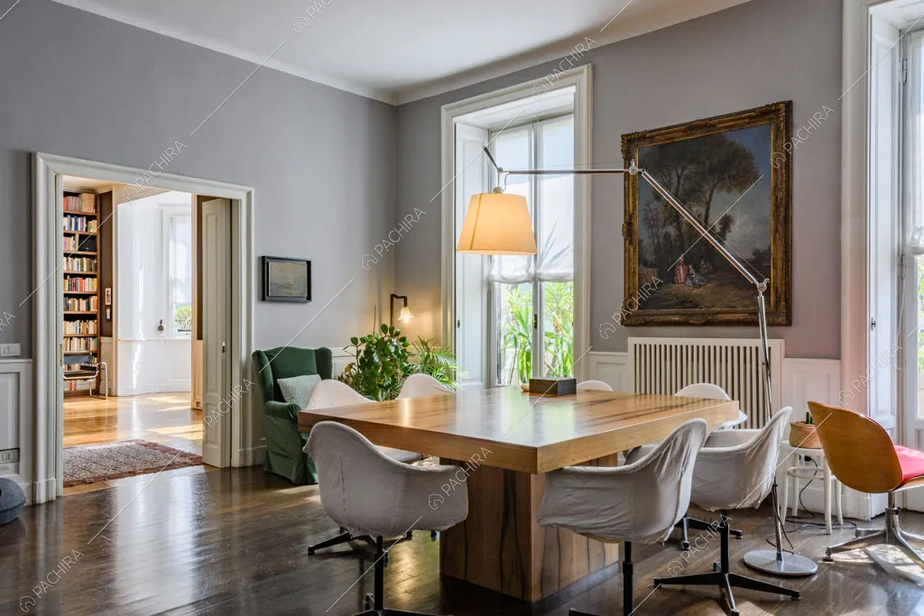 Sala da pranzo con tavolo quadrato in legno, pareti grigie con boiserie e pavimento in parquet