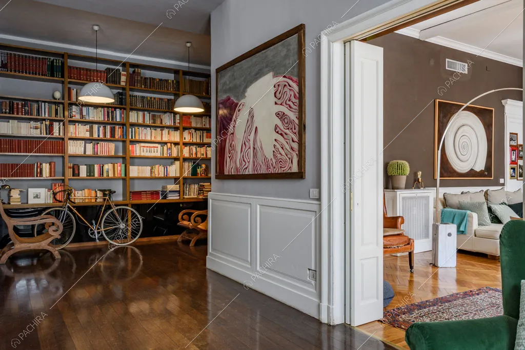 Sala da pranzo con libreria a tutta parete, boiserie e scorcio sulla sala