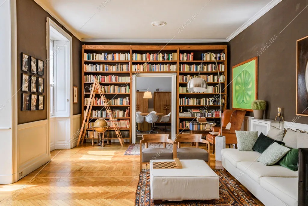 Luminosa sala con pavimento in parquet a spina di pesce e libreria e tutta parete