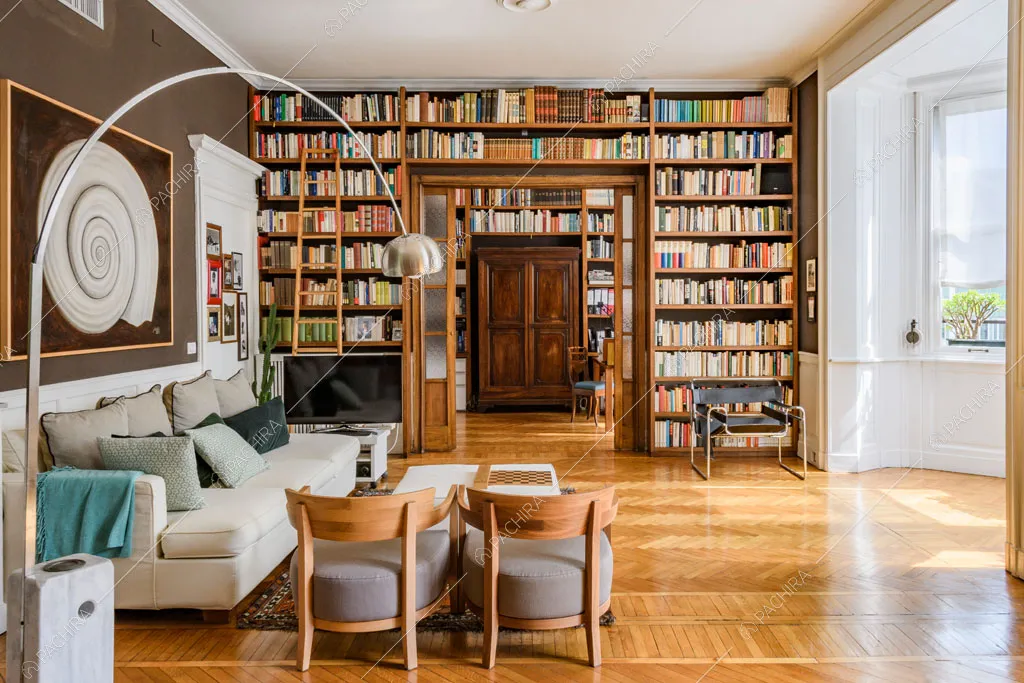 Dalla sala da pranzo vista sul soggiorno con bow window, libreria a parete e lampada di design