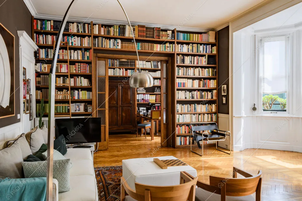 Luminosa sala con libreria a tutta parete, scorcio sullo studio e bow window con boiserie