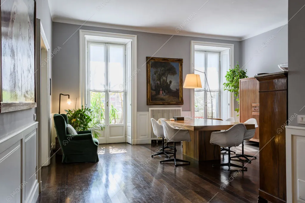 Vista sulla sala da pranzo con boiserie alle pareti, porte-finestre e pavimento in parquet