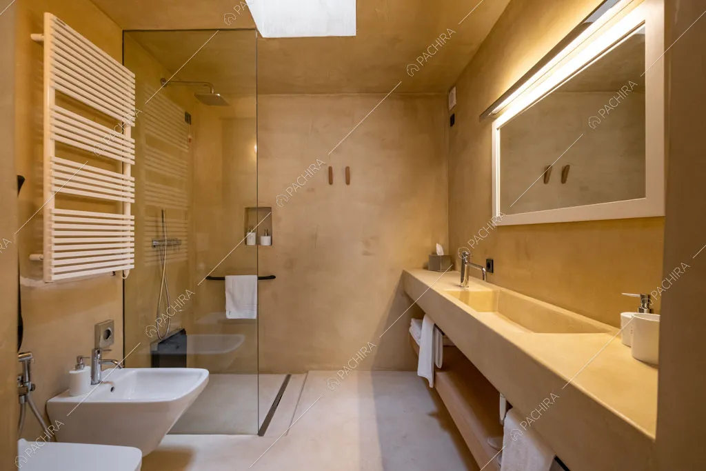 Ampio bagno con pareti dorate, lungo lavandino e box doccia